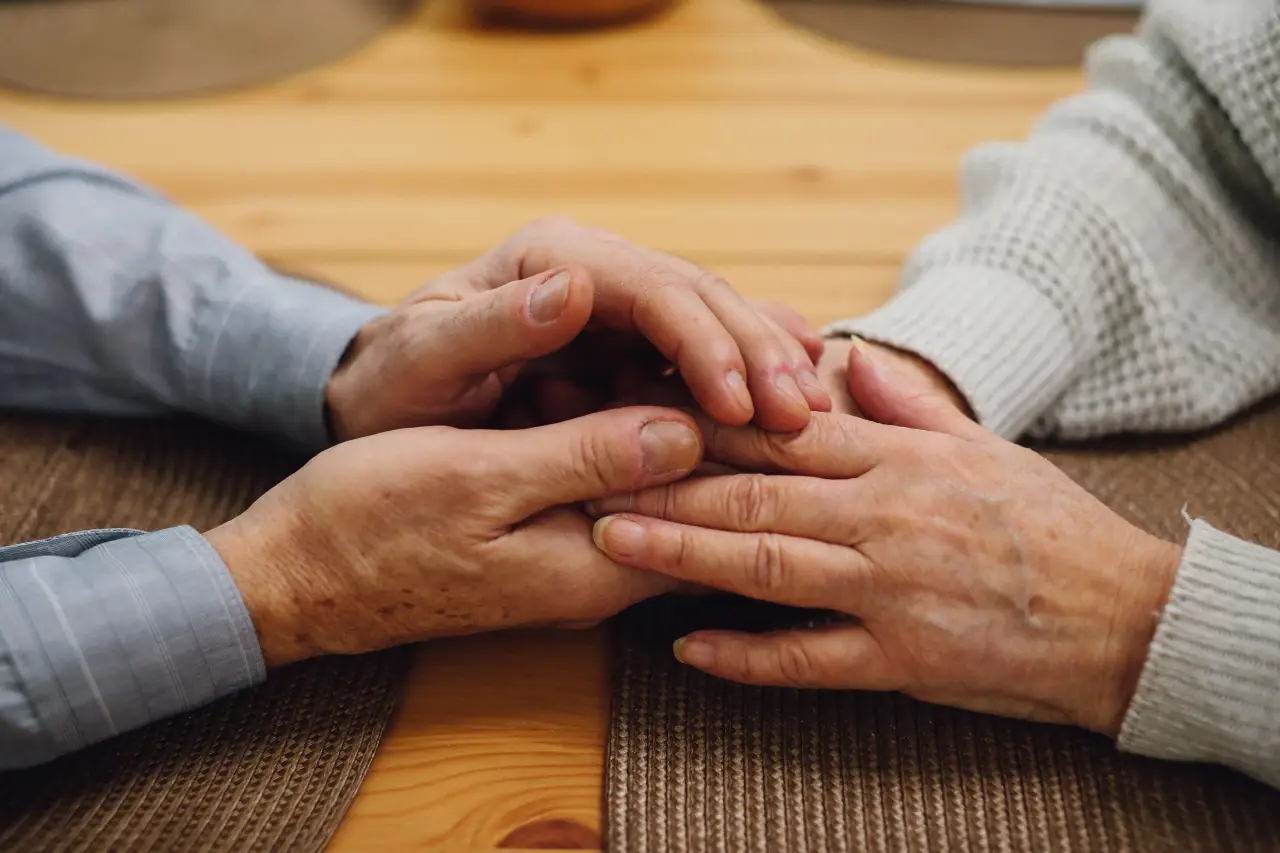 Duas pessoas de mãos dadas sobre a mesa de casa
